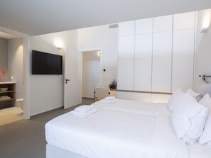 Une chambre d’hôtel moderne dotée d’un grand lit, d’un téléviseur à écran plat fixé au mur, d’une table de chevet avec une lampe et d ’une armoire avec des portes coulissantes.