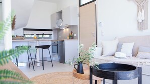 Una cocina moderna con barra, una mesa de comedor con sillas, un sofá con cojines y una planta en maceta.