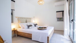 Un dormitorio con cama, mesita de noche, lámpara y ventana con cortinas.