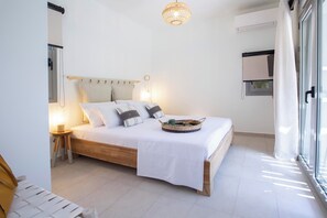 Ein Schlafzimmer mit Bett, Nachttisch, Lampe und einem Fenster mit Vorhängen.