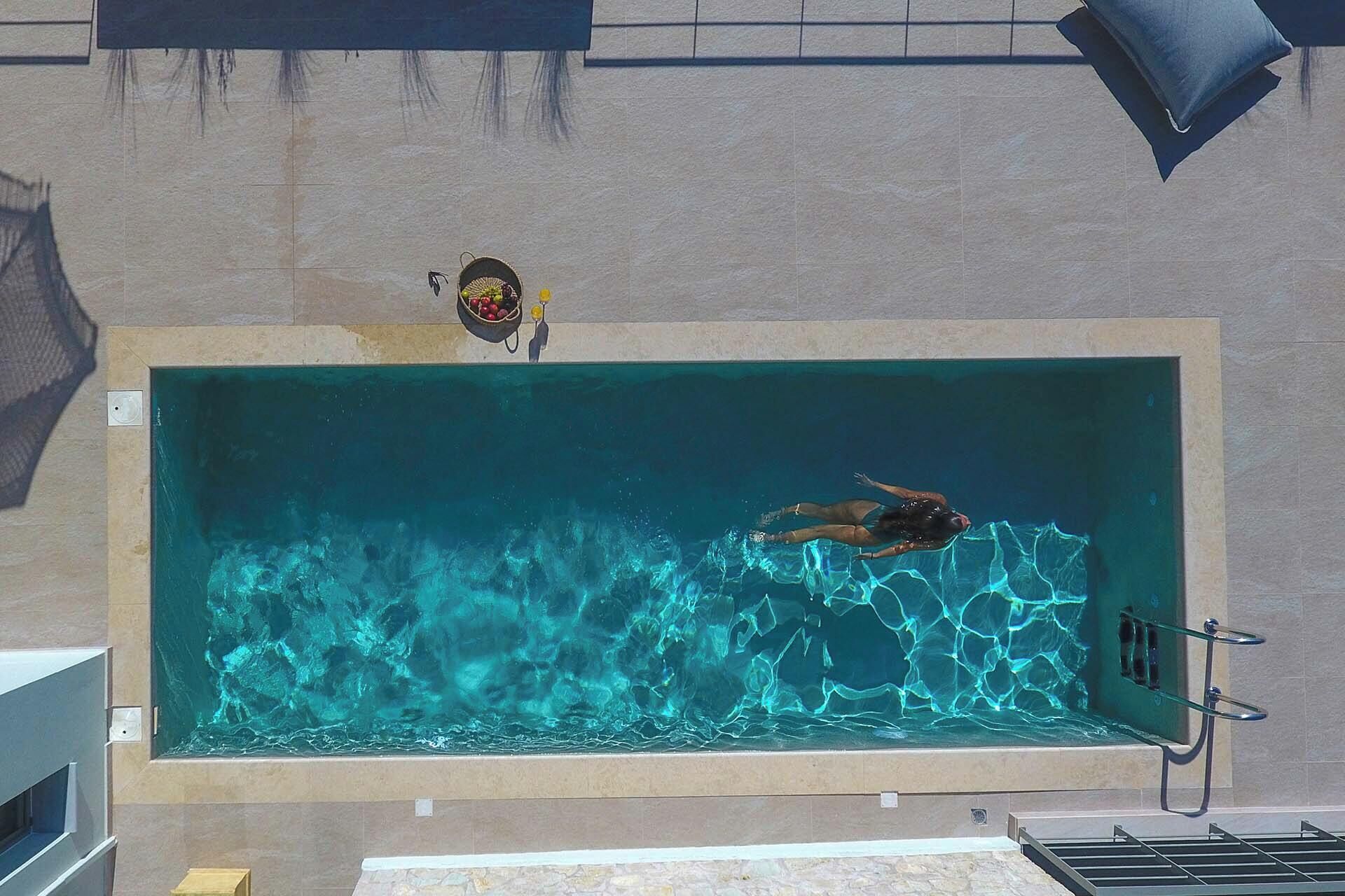 Ein Schwimmbad mit einer schwimmenden Person, einem Handtuchhalter und einem kleinen Regal mit Gegenständen.