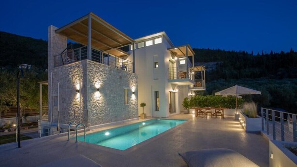 Una casa moderna con piscina, mobiliario exterior y fachada de piedra.