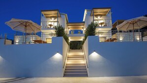 Un moderno edificio de varios pisos con una escalera central, asientos exteriores y vista al mar.