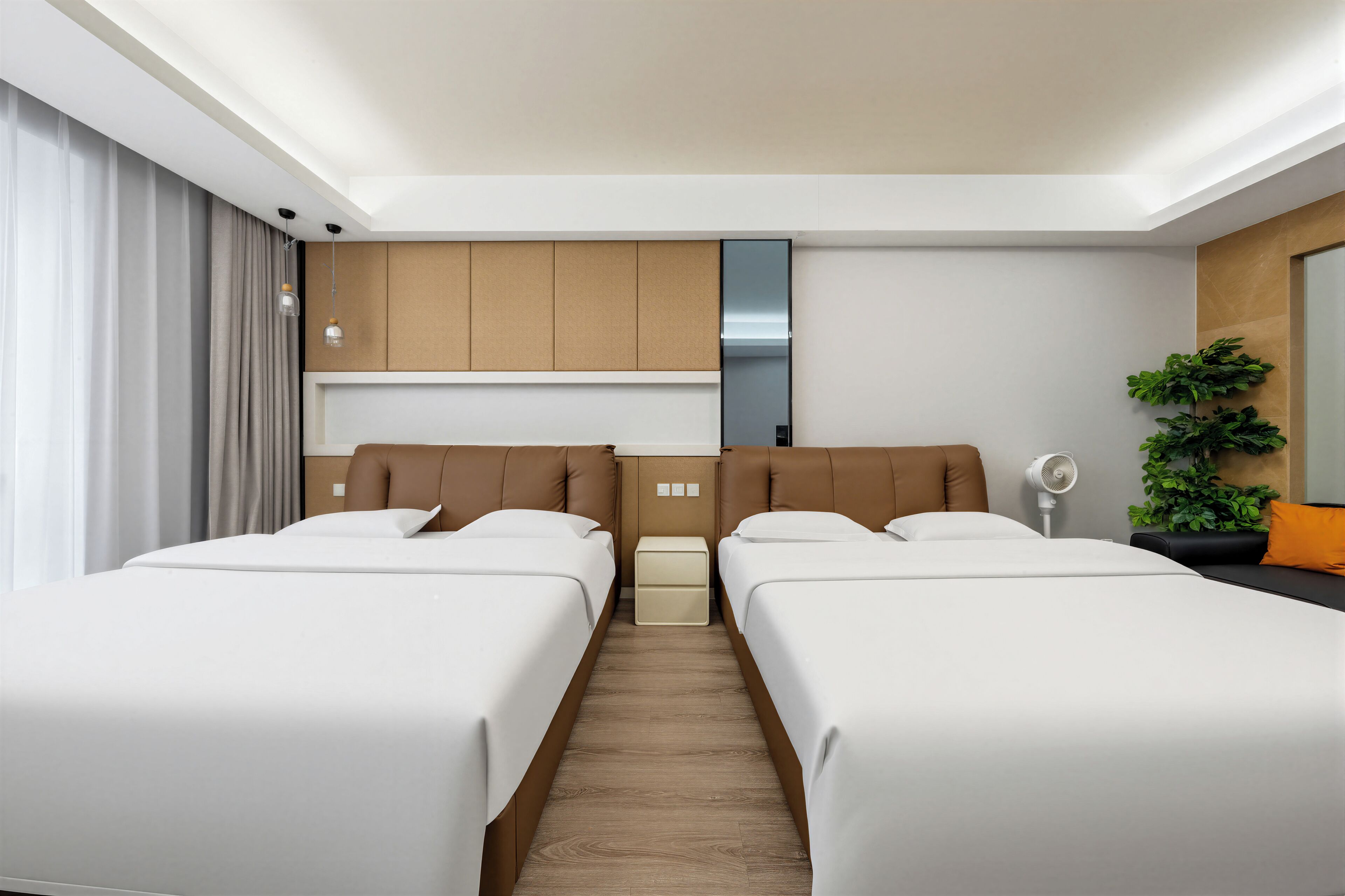 Une chambre d’hôtel avec deux lits, une petite table de chevet, un miroir et une plante en pot.