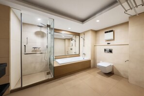 Un baño moderno con ducha acristalada, un espejo grande, un lavamanos blanco y un inodoro.