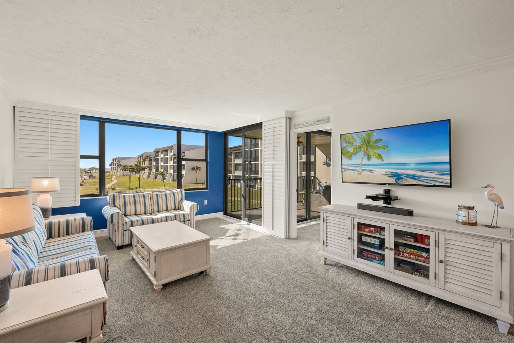 A living room with a TV, a sofa, a coffee table, and a cabinet with board games.
