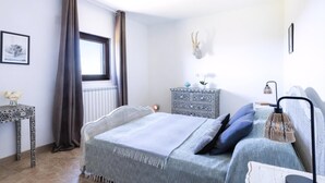 Een slaapkamer met een bed, nachtkastje, lamp en een decoratief hoofdeinde.
