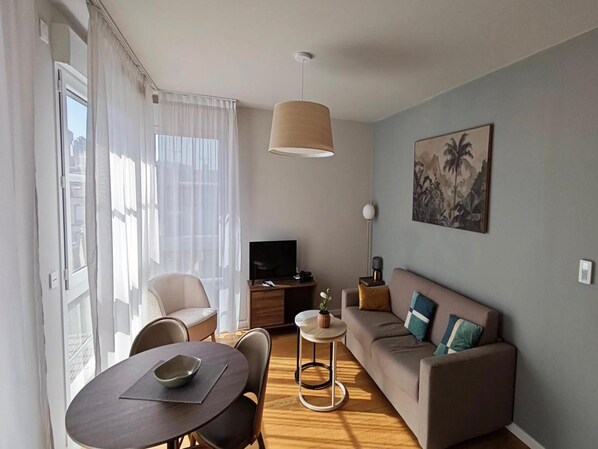 Una sala moderna con sofá, una mesa de comedor y televisor.