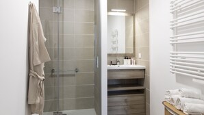 Un bagno moderno con cabina doccia in vetro, lavabo con specchio e porta asciugamani.