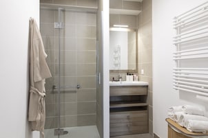Un baño moderno con cabina de ducha de vidrio, tocador con espejo y perchero.