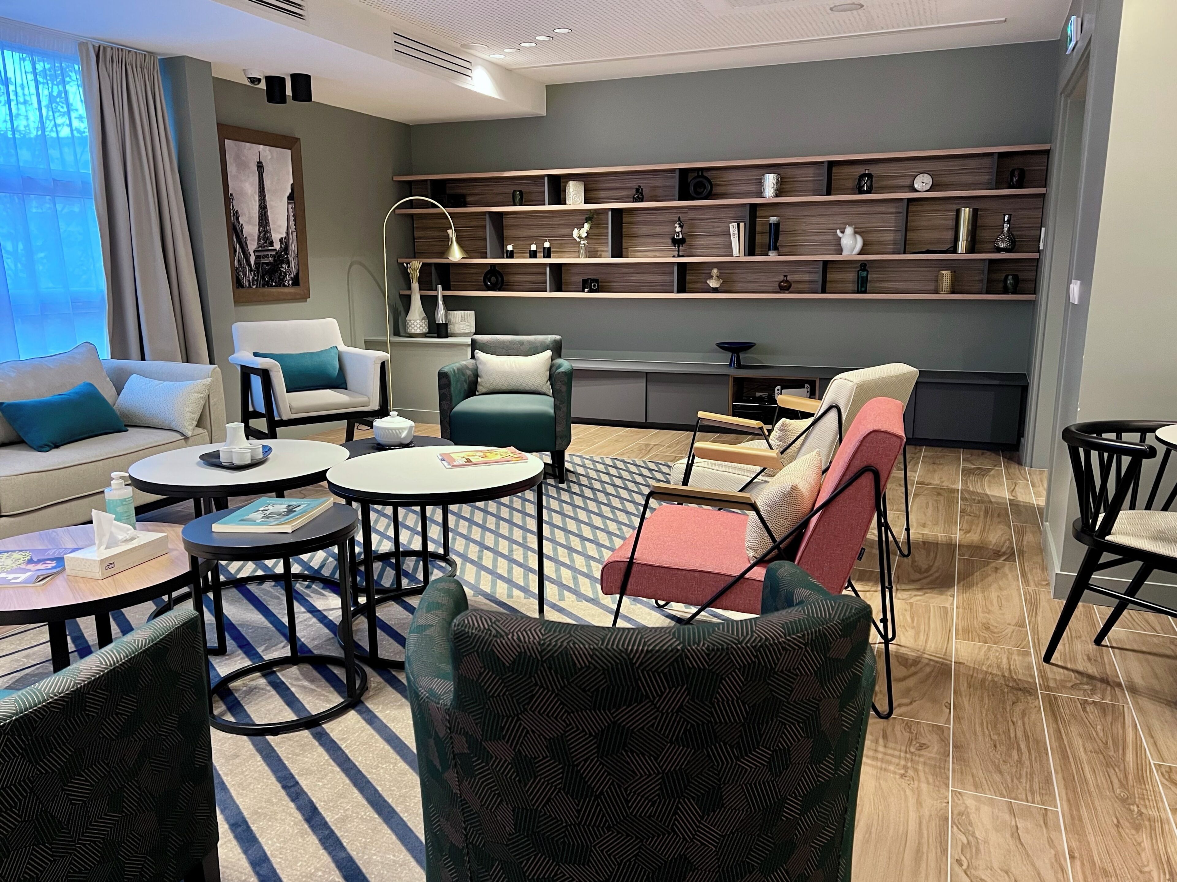 Uma sala de estar moderna com sofá, poltronas, mesa de centro, estante e área de jantar.