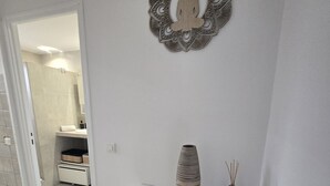 A modern bathroom with a white vanity, a decorative wall piece, and a vase with reed diffusers. - U Miu Sognu by Pinarello Villa Services (Sainte-Lucie de Porto-Vecchio)