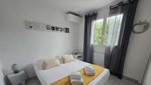 A hotel room with a bed, a bedside table, a lamp, a window with curtains, and a wall decoration. - U Miu Sognu by Pinarello Villa Services (Sainte-Lucie de Porto-Vecchio)