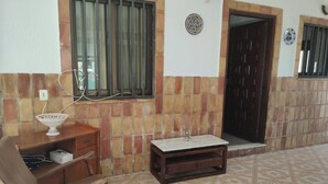 A room with a tiled floor, a wooden desk, a chair, a small table, and a door. - Country house near the sea in a quiet area (Oliva)