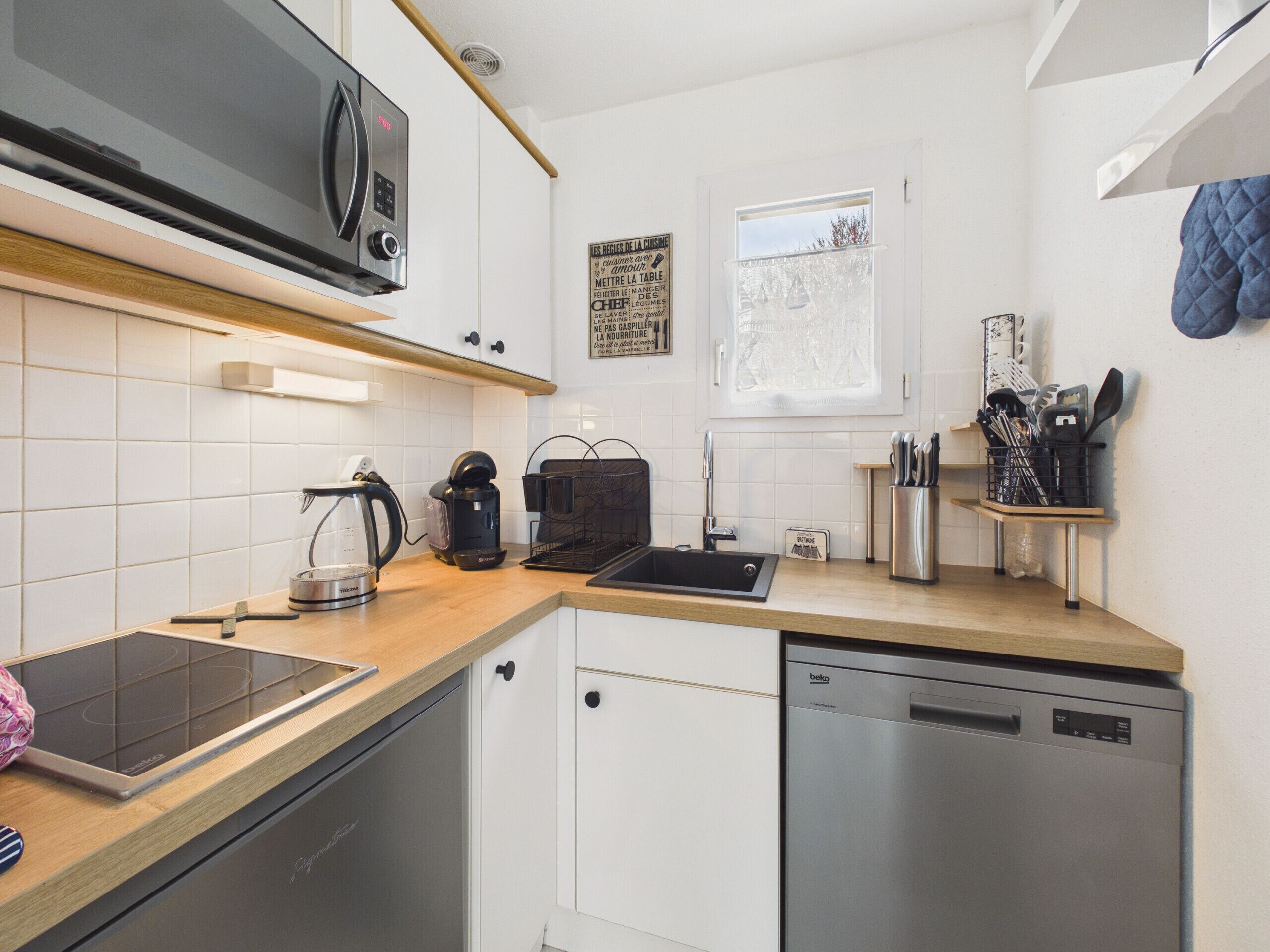 Eine moderne Küche mit Mikrowelle, Kaffeemaschine, Wasserkocher, Spüle und Geschirrspüler.