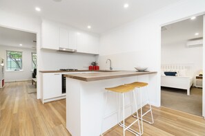 A modern kitchen with white cabinetry, a wooden countertop, and two bar stools.