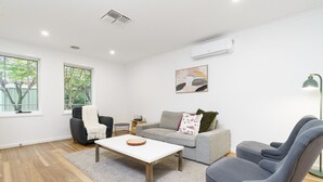 A modern living room with a grey sofa, a white coffee table, and a grey armchair.