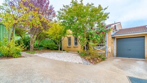 A residential property with a gravel driveway, a garage, and a small garden with trees and shrubs.