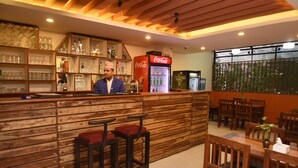 A bar area with wooden shelves, a Coca-Cola refrigerator, and seating arrangements. - Hotel Central Prime (Kathmandu)