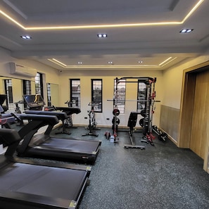 Et fitnessrum med løbebånd, vægtbænk og squat-stel.