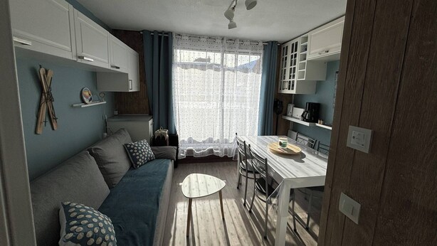 Ett kompakt bostadsutrymme med en soffa, ett matbord och ett köksområde.