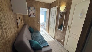 En hall med en soffa, träväggar, en dörr och utsikt över ett utomhusområde.
