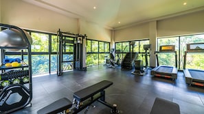 A gym with various exercise equipment, large windows, and a bench. - Naumi N544 | 2BR Ocean View in Playas del Coco + Pools (Sardinal)