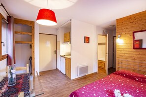 Ein Zimmer mit einem Bett, einem Holzschrank, einem Spiegel, einer roten Lampe und einem kleinen Tisch mit einer Vase.