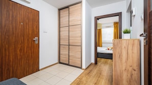 Una habitación con un armario de madera, una puerta corredera, una cama con cortina amarilla y una planta pequeña sobre un mueble de madera.