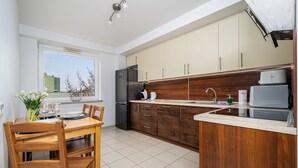 Una cocina moderna con armarios de madera, horno empotrado y comedor con mesa y sillas.