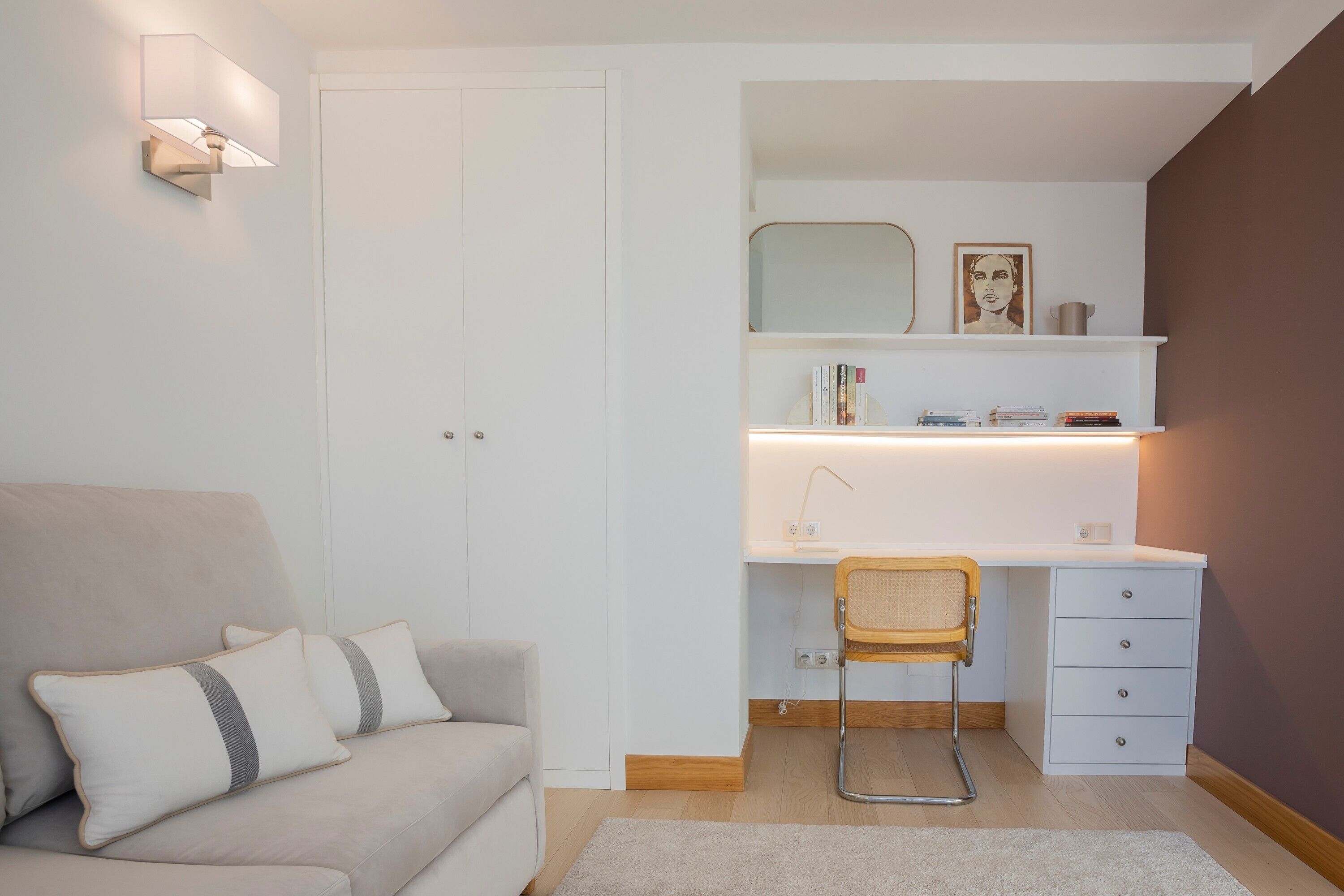 Een moderne slaapkamer met een bed, bureau, stoel en een kledingkast.