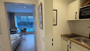 A modern kitchen with a wooden countertop, a built-in oven, and a window overlooking a snowy landscape. - Balcony apartment | near the lake | climate | near Bremen (Ganderkesee)