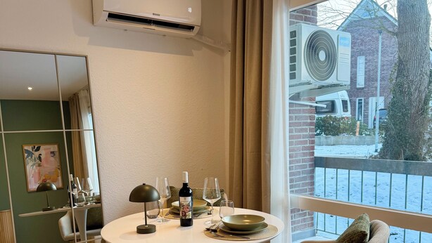 A modern dining area with a round table, chairs, and a view of a snowy street. - Balcony apartment | near the lake | climate | near Bremen (Ganderkesee)