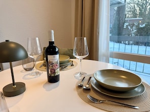Ett matbord med en vinflaska, glas, tallrikar och bestick.