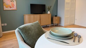 A dining area with a table set for two, a television on a wooden cabinet, and a door to the right. - Balcony apartment | near the lake | climate | near Bremen (Ganderkesee)