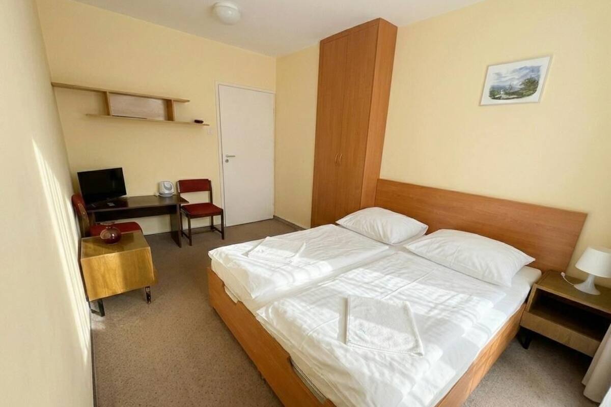 Ein Hotelzimmer mit einem Bett, einem Schreibtisch, einem Stuhl, einem Fernseher und einem Bild an der Wand.