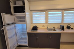 A compact kitchen with a built-in microwave, a sink, and a window with blinds. - Zen - Near Basel | Japanese atmosphere & calm (Saint-Louis)