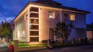 Ein modernes Gebäude mit einem Schild, auf dem 'Villa 68 Residence' steht, einem Balkon und einem gut beleuchteten Eingang.