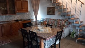 Ein Essbereich mit Tisch und Stühlen, eine Küche mit Schränken, eine Treppe und ein Sofa.