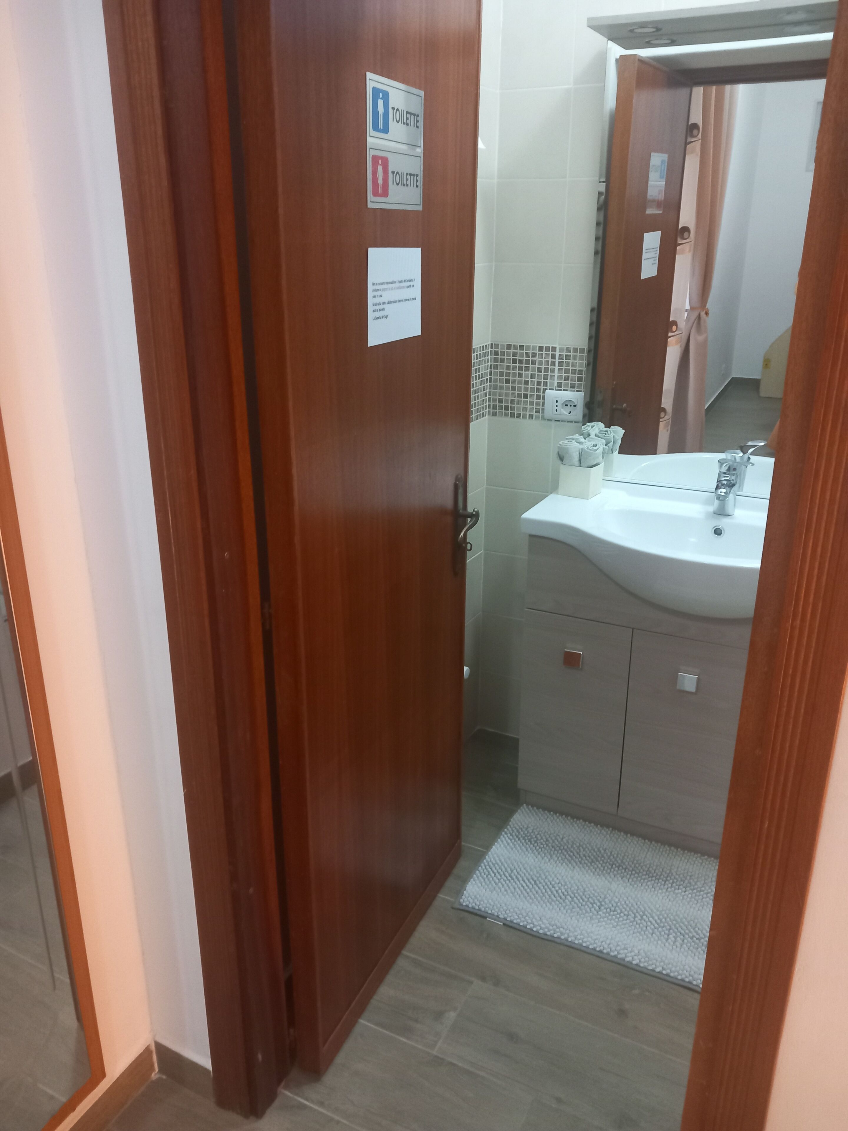 Una porta di legno con un cartello che indica un bagno.