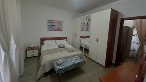 Ein Schlafzimmer mit einem Bett, Nachttischen, einem Kleiderschrank, einer Bank und einem Bild an der Wand.