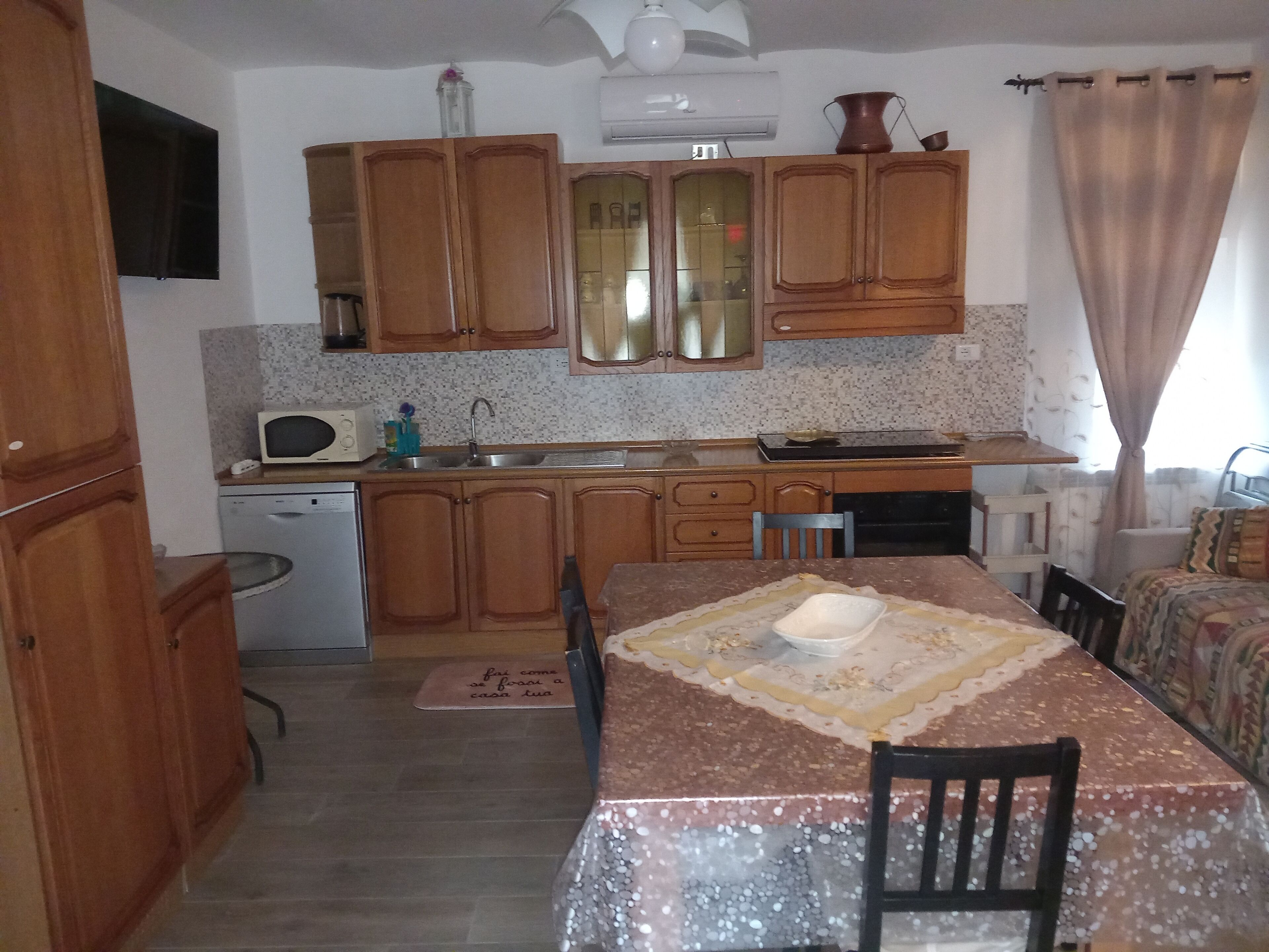 A compact kitchen with wooden cabinets, a microwave, and a dining table with chairs.