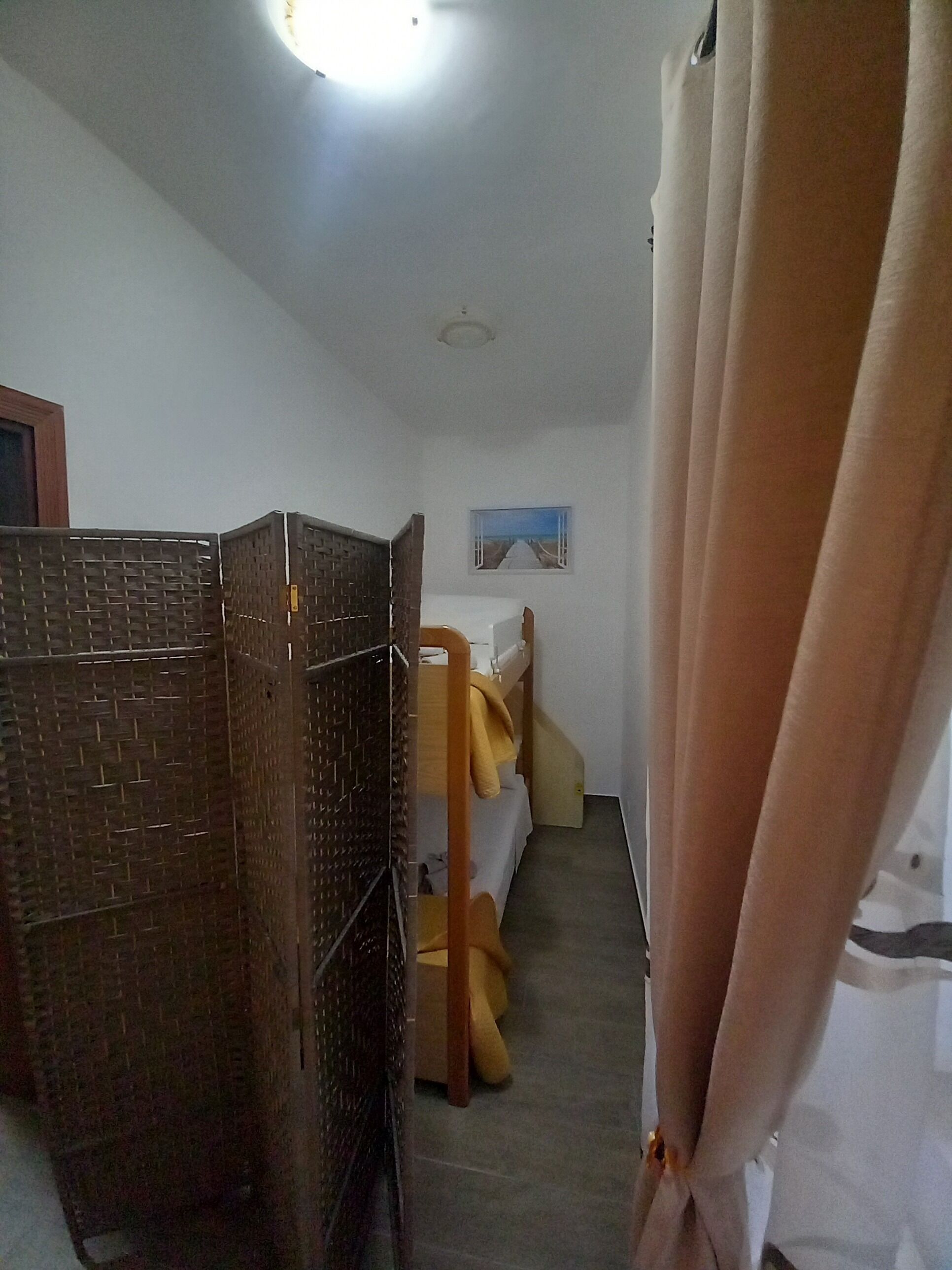 Quarto com uma cama beliche, uma pequena mesa, uma cadeira e um quadro na parede.