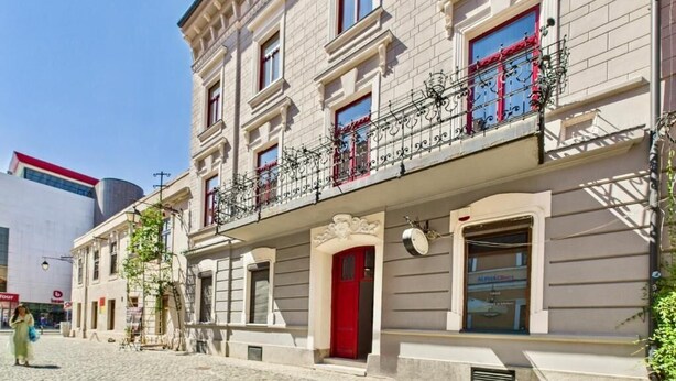 A building with a red door, multiple windows, and a balcony with decorative railings. - Griselini Boutique Suites (Timișoara)