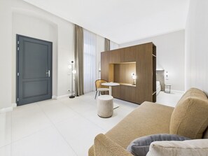 A modern hotel room with a large bed, a small round table, a sofa, and a wooden partition. - Griselini Boutique Suites (Timișoara)
