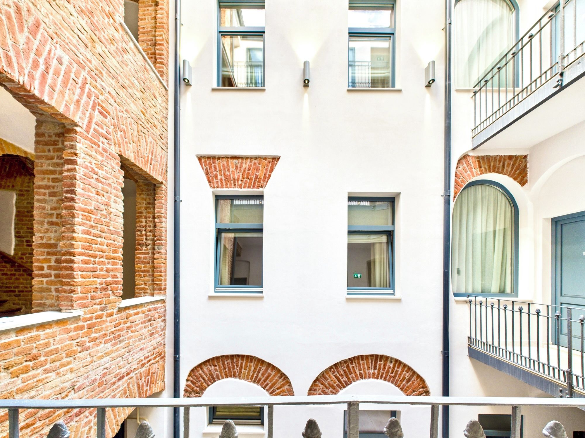 A multi-story building with brick and white facades, multiple windows, and balconies.