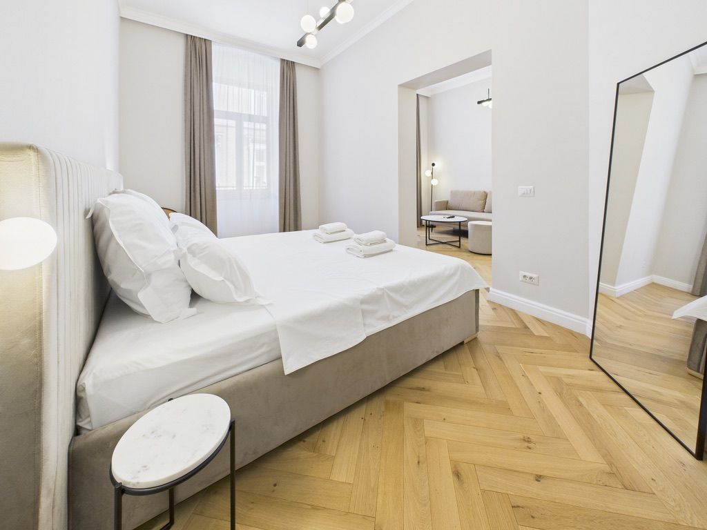 Un dormitorio moderno con cama, mesita de noche y un espejo grande.