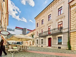 A cobblestone street with outdoor seating, a café, and historic buildings. - Griselini Boutique Suites (Timișoara)
