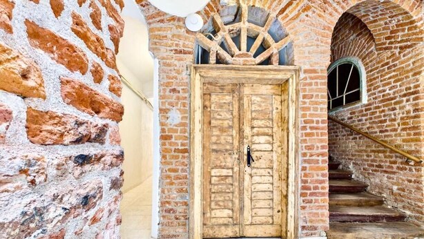 A rustic brick building with a wooden door, a stone wall, and a staircase leading to an arched doorway. - Griselini Boutique Suites (Timișoara)