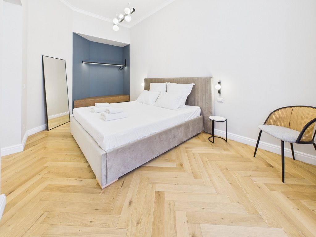 Un dormitorio moderno con una cama grande, una mesita de noche, una silla y un espejo.